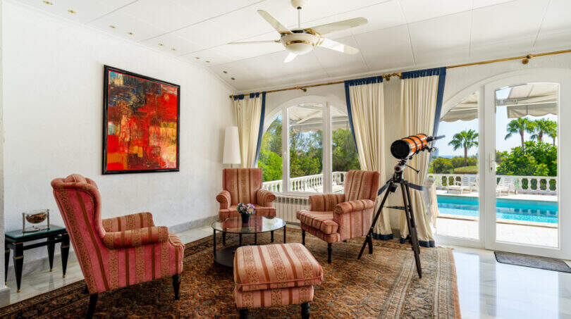 Elegantes Wohnzimmer mit Antiquitäten, Teleskop und Blick auf den Pool der Villa in Cala Murada.
