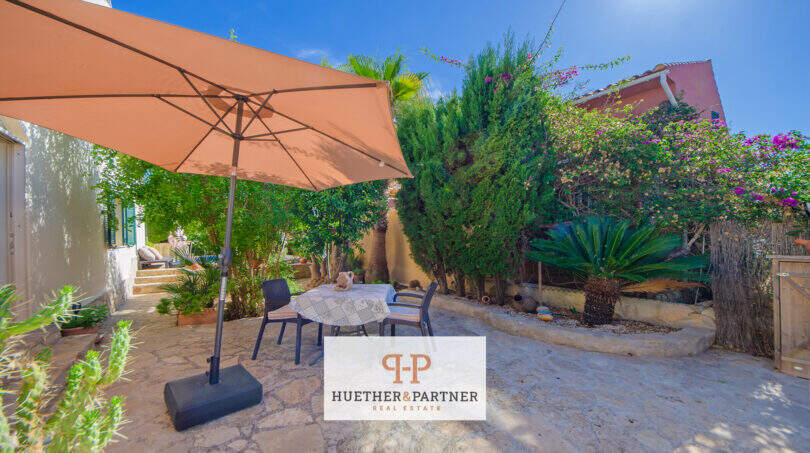 Gepflegte Terrasse mit Sonnenschirm, Sitzgruppe und mediterranem Garten in Cala Murada