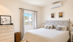 Helles Schlafzimmer mit Doppelbett, Klimaanlage und Meerblick aus Fenster in Villa Santanyí