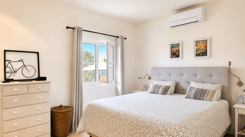 Helles Schlafzimmer mit Doppelbett, Klimaanlage und Meerblick aus Fenster in Villa Santanyí