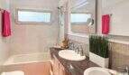 Modernes Badezimmer mit Badewanne, Dusche, Doppelwaschbecken und pinken Handtüchern im Wohlfühlhaus Santanyí