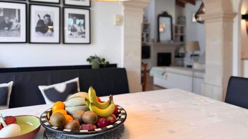 Elegantes Esszimmer mit Obstschale, schwarzen Designerstühlen und Kunstfotos in Santanyí-Wohlfühlhaus