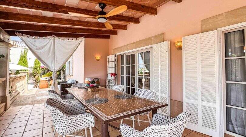 Überdachte Terrasse mit Holzbalkendecke, Deckenventilator, mosaikgefliestem Esstisch und Rattanstühlen in Santanyí