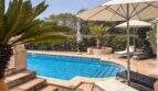 Privater Pool mit Natursteinteasse, Liegestühlen und üppigem Grün der Finca in Santanyí