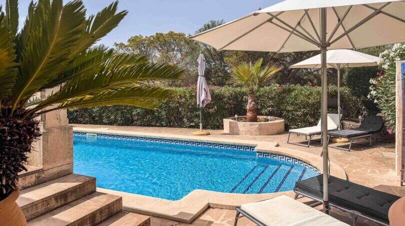 Privater Pool mit Natursteinteasse, Liegestühlen und üppigem Grün der Finca in Santanyí