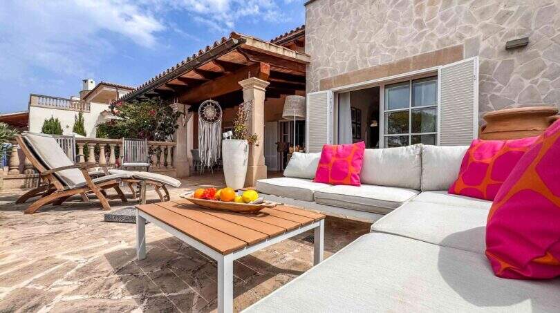 Mediterrane Terrasse mit Lounge-Bereich, Natursteinwand und Holzpergola des Wohlfühlhauses in Santanyí