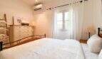 Helles Schlafzimmer mit Doppelbett, Klimaanlage, weißer Kommode und Fenster zur Gartenansicht in Santanyí