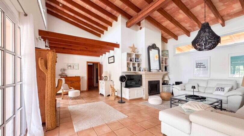 Helles Wohnzimmer mit Holzbalkendecke, Kamin und weißen Sofas im Wohlfühlhaus nahe Santanyí