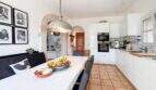 Helle Wohnküche mit weißen Fronten, Terrakottaboden, Esstisch und Rundbogen in exklusiver Villa in Santanyí