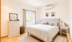 Helles Schlafzimmer mit Doppelbett, weißer Kommode, Klimaanlage und Fenster mit Meerblick in Santanyí