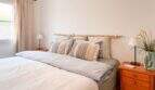 Helles Schlafzimmer mit Doppelbett, Bambus-Kopfteil, Holznachttischen und natürlichen Erdtönen im Wohlfühlhaus Santanyí