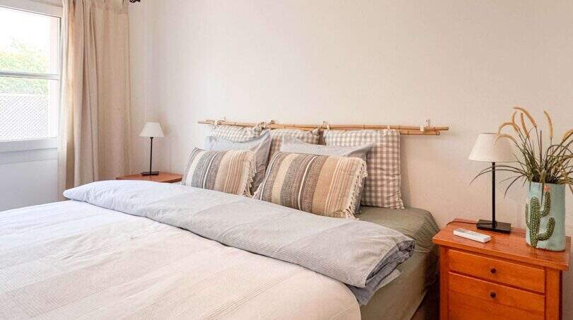 Helles Schlafzimmer mit Doppelbett, Bambus-Kopfteil, Holznachttischen und natürlichen Erdtönen im Wohlfühlhaus Santanyí