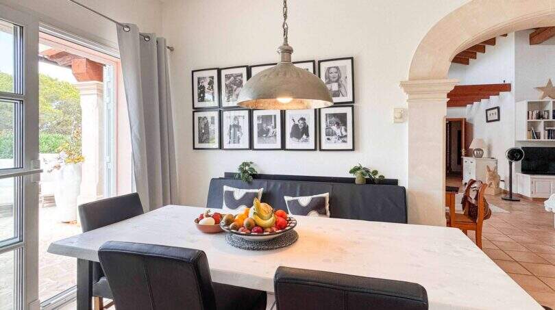Helles Esszimmer mit Marmortisch, schwarzen Lederstühlen, Pendelleuchte und Galerie-Wand in exklusiver Villa Santanyí