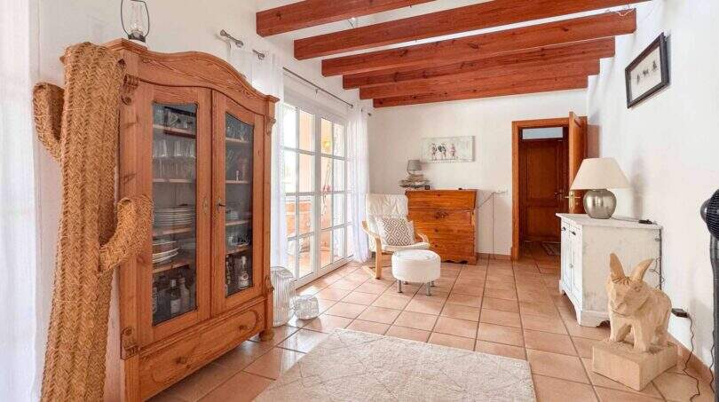 Helles Wohnzimmer mit Holzbalkendecke, Terrakottaboden, Holzschrank und Terrassentür in Santanyí