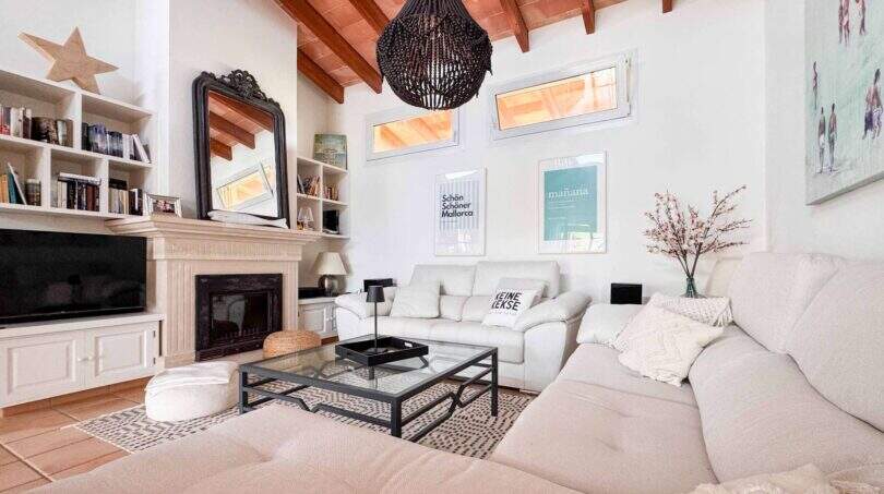 Helles Wohnzimmer mit weißen Sofas, Kamin, Holzbalkendecke und mediterranem Flair in Santanyí