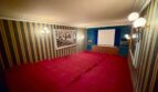 Kinoraum mit rotem Teppich, Projektionswand, Streifentapete und Wandleuchten in Retro-Villa Porto Cristo.