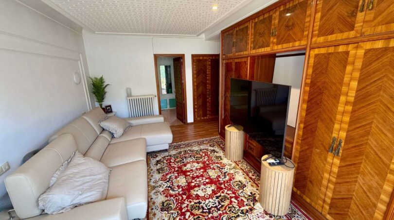 Wohnzimmer der Retro-Villa in Porto Cristo mit Ledersofa, Orientteppich und elegantem Holzschrank mit TV.