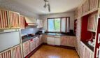 Geräumige Retro-Küche mit rot-weißen Streifenschränken, dunkler Arbeitsplatte und Holzboden in Villa Porto Cristo.