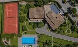 Luftaufnahme der Villa in Porto Cristo mit Tennisplatz, Pool und gepflegtem Garten.