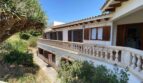 Außenansicht der Retro-Villa in Porto Cristo mit Balustrade, Holzläden und üppigem Grün.