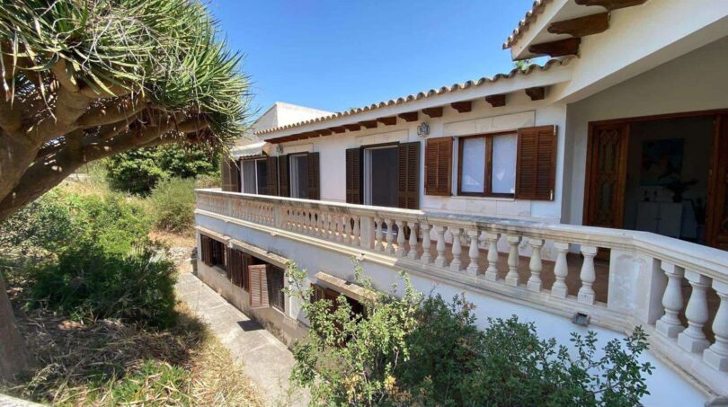 Außenansicht der Retro-Villa in Porto Cristo mit Balustrade, Holzläden und üppigem Grün.
