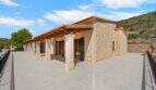 Außenterrasse der Finca in Cala Murada mit Natursteinmauern, Holzbalken-Pergola und großzügigem Fliesenboden