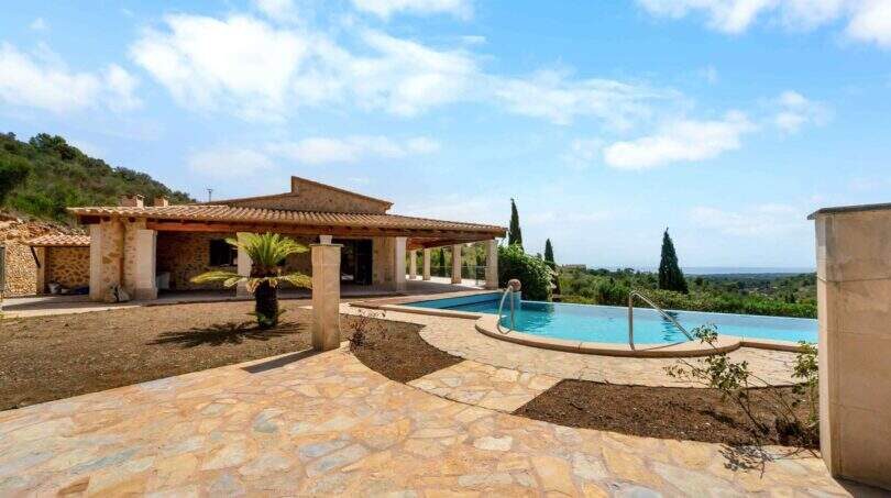 Außenbereich der Finca in Cala Murada mit Natursteinterrasse, Infinity-Pool und Meerblick