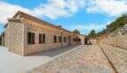 Außenansicht der mallorquinischen Finca in Cala Murada mit traditioneller Natursteinmauer und gepflastertem Innenhof.