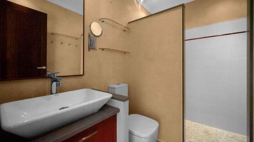 Modernes Badezimmer der Finca Cala Murada mit Aufsatzwaschbecken, Glasdusche und rotem Waschtischunterschrank.