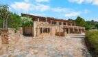 Außenansicht der mallorquinischen Finca in Cala Murada mit Natursteinmauern, Terrasse und gepflastertem Innenhof.
