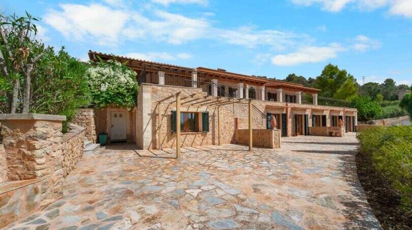 Außenansicht der mallorquinischen Finca in Cala Murada mit Natursteinmauern, Terrasse und gepflastertem Innenhof.