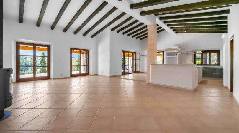 Geräumiges Wohnzimmer mit Küche, Holzbalkendecke und Terrakottaboden der Finca in Cala Murada