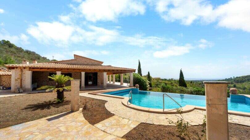 Außenbereich der Finca in Cala Murada mit großem Swimmingpool, Natursteinterrasse und Meerblick.