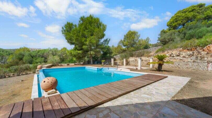 Außenpool der Finca in Cala Murada mit Holzdeck, Natursteinmauer und mediterraner Bepflanzung.