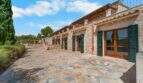 Außenansicht der Finca in Cala Murada mit Natursteinmauern, grünen Fensterläden und gepflastertem Innenhof.