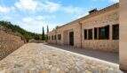 Außenbereich der Finca in Cala Murada mit Natursteinmauern, Kopfsteinpflaster und mediterranen Zypressen