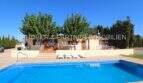 Finca in Son Carrió with large pool, sun loungers, terrace and shade-providing trees under blue sky.