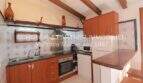 Rustic built-in kitchen with wooden beam ceiling, cooking area and tile backsplash in finca on Mallorca