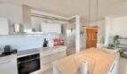Moderne weiße Einbauküche mit Kochinsel, Backofen und Kühlschrank in sonniger Wohnung in Palmanova