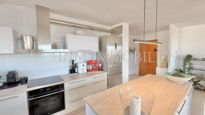 Moderne weiße Einbauküche mit Kochinsel, Backofen und Kühlschrank in sonniger Wohnung in Palmanova