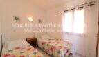 Bright bedroom with two single beds, floral bedding, air conditioning and white curtains in Mallorca finca.