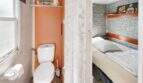 Blick ins WC mit orangefarbener Wand und angrenzendem Schlafzimmer mit Steinoptik-Tapete, Finca Algaida