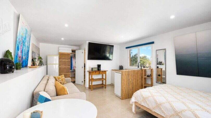 Helles Studio-Apartment der Finca Algaida mit Bett, Sofa, TV, Miniküche und Naturholz-Akzenten.