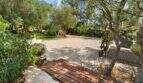 Naturnaher Garten der Finca Algaida mit Holzdeck, Kiesfläche und alten Olivenbäumen auf 14.206 m²
