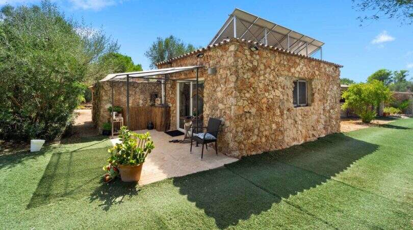 Rustikales Steinhaus der Finca Algaida mit Solarpanelen, überdachter Terrasse und gepflegtem Rasen