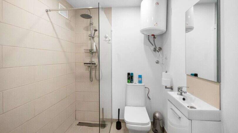 Modernes Badezimmer der Finca Algaida mit begehbarer Dusche, WC, Waschbecken und Warmwasserspeicher.