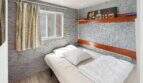 Schlafzimmer der Finca Algaida mit Steinwand, Holzregalen, Doppelbett und Buddha-Kunstwerk