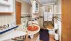 Badezimmer der Finca Algaida mit runder Waschbeckenablage, Glasdusche und Holzakzenten.