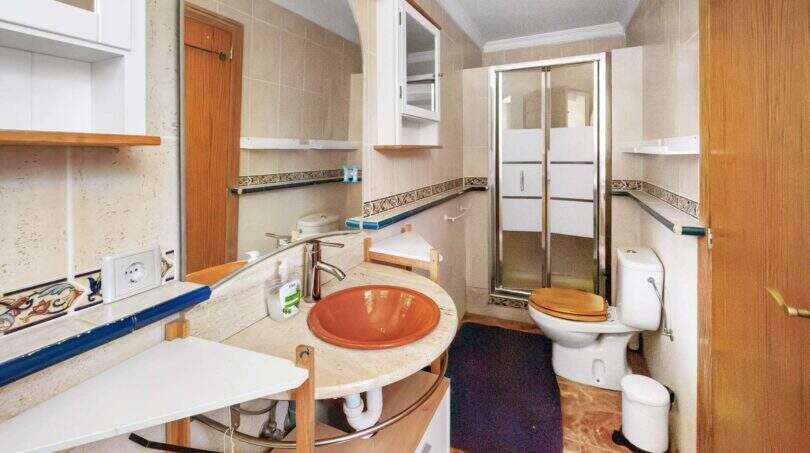 Badezimmer der Finca Algaida mit runder Waschbeckenablage, Glasdusche und Holzakzenten.