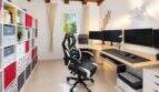 Heimarbeitszimmer der Finca Algaida mit Gaming-Stuhl, drei Monitoren, L-Schreibtisch und Regal mit Holzbalkendecke.